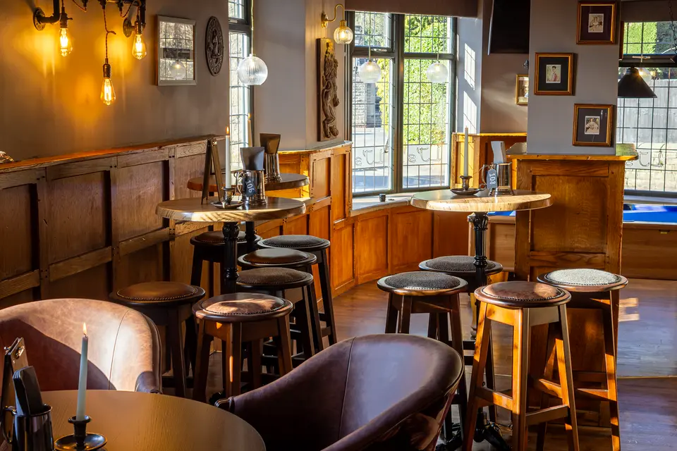 Bar stools along the counter at The Little John, beneath pendant lights