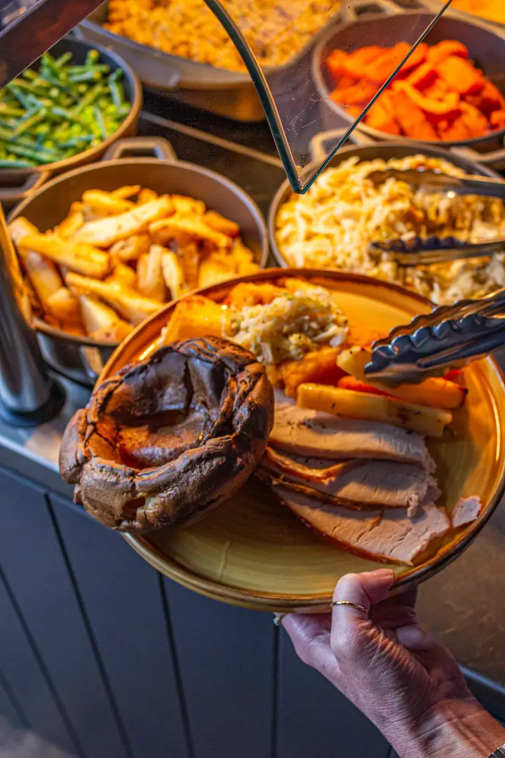 A carvery plate of sliced roast meats with a Yorkshire pudding, roast potatoes, parsnips and cauliflower cheese