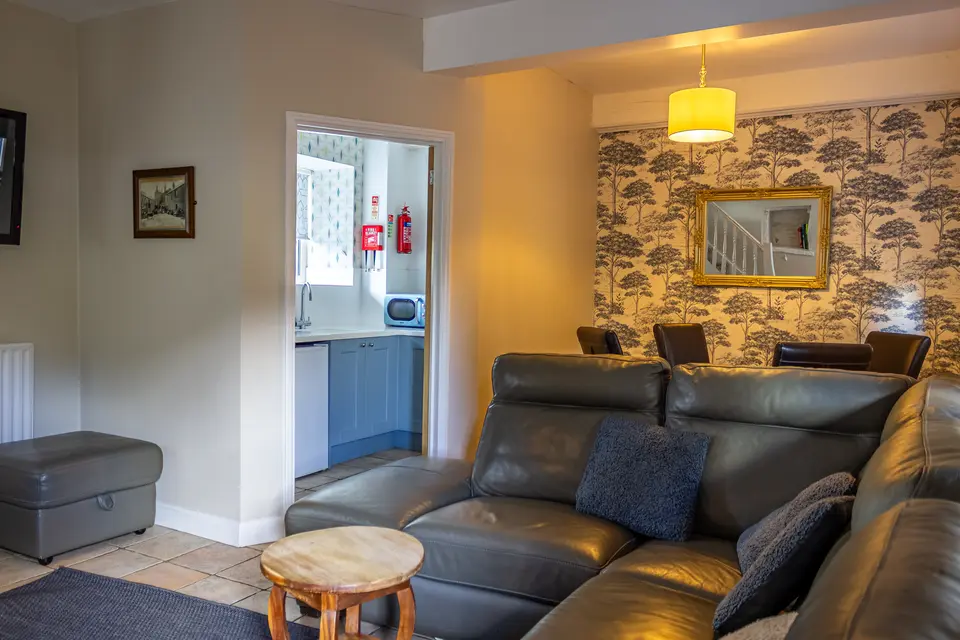 A cottage lounge with a leather corner sofa and hallway beyond