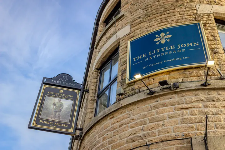 The Little John hanging sign and Free House sign against a blue sky